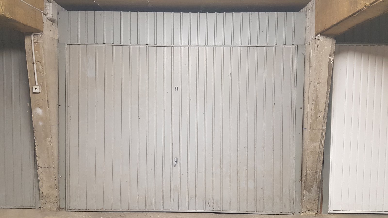 Porte garage basculante avant Porte de garage basculante grise forcée avant remplacement | Box en sous-sol à Aix-les-Bains | C-Zam