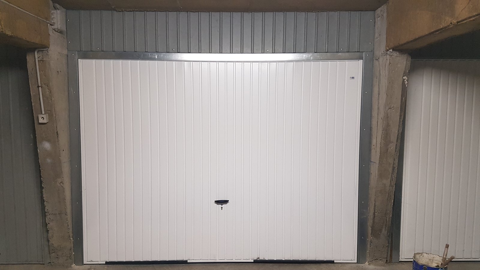 Porte garage basculante après Porte de garage basculante blanche neuve installée dans un box en sous-sol | Aix-les-Bains | C-Zam